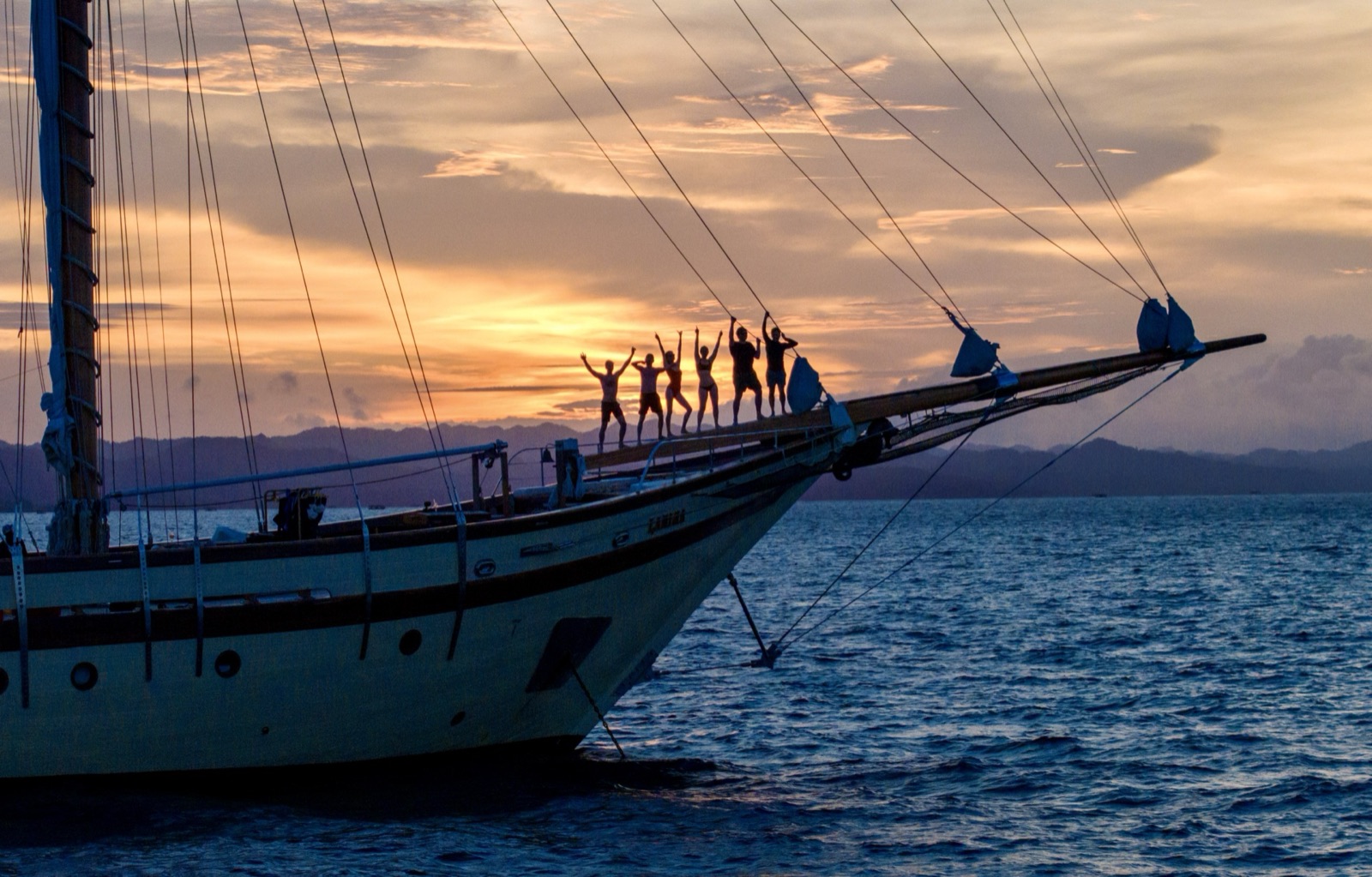 Aerial — a schooner anchored among karsts at sunrise.