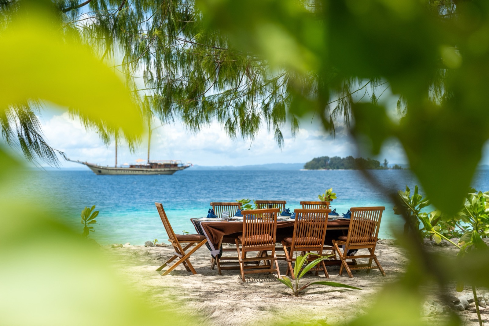 Beach dining setup with the schooner at anchor in the distance.